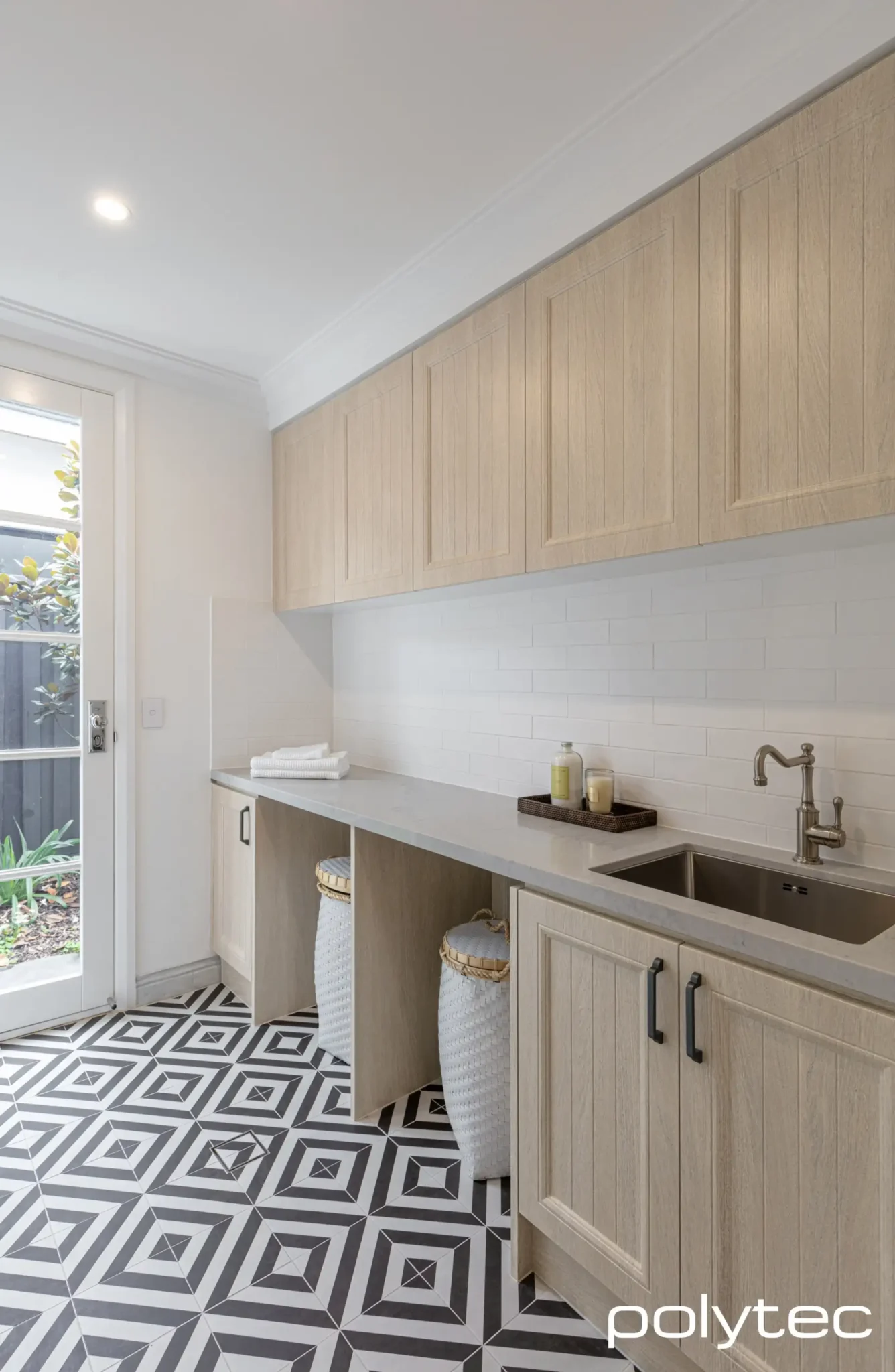 A laundry room with a black-and-white checkered floor, a washer and dryer, and a laundry sink.