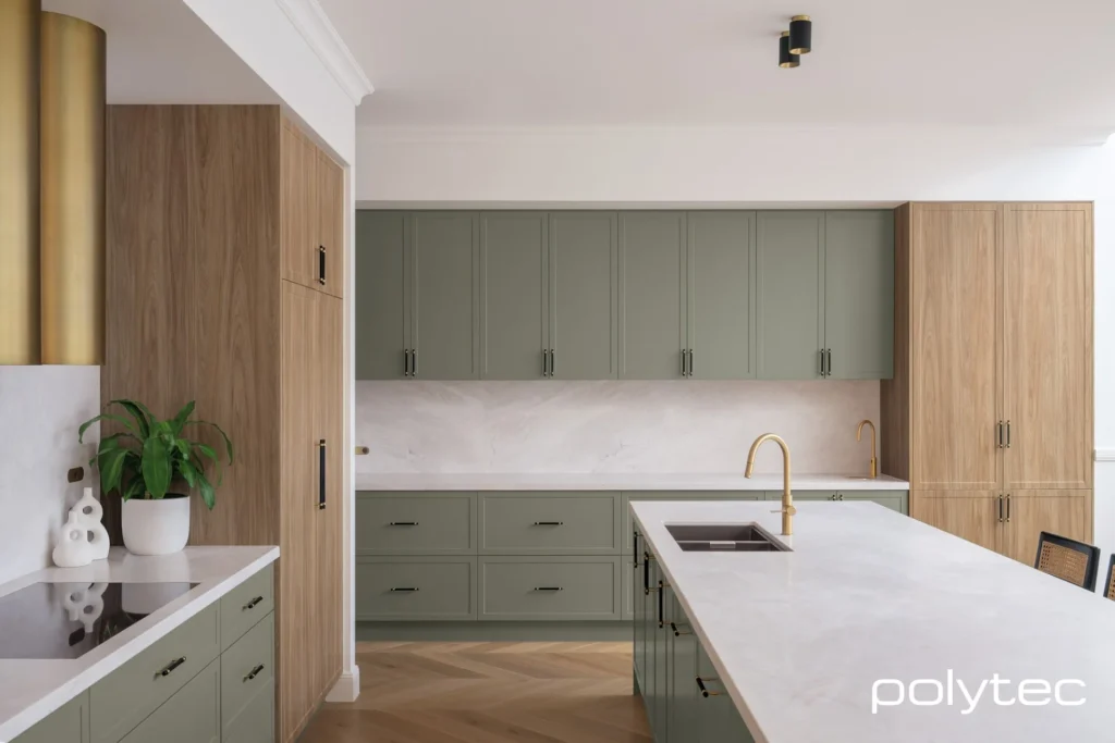 Modern kitchen with green wooden cabinets, white countertops, and stainless steel faucets.